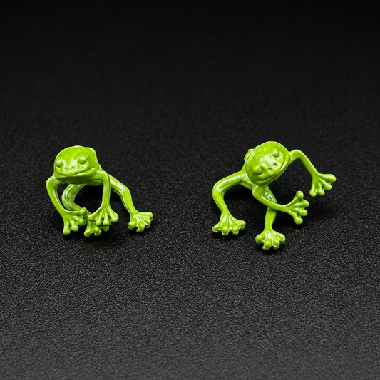 Two bright green frog-shaped stud earrings displayed side by side on a dark textured background.