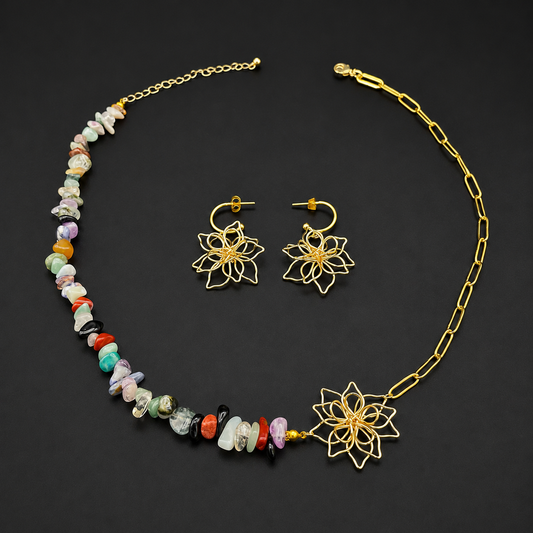 A gold-tone necklace and matching drop earrings set on a black background. The necklace features a beaded strand with multicolored stone chips and a large gold lotus flower at the end, paired with a chain link section and clasp closure.