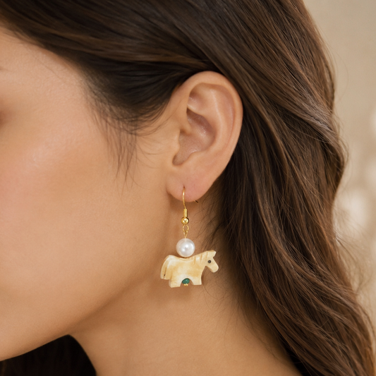  woman wearing a delicate gold dangle Hand-Carved Natural Bone Horse & Pearl Dangle Earrings