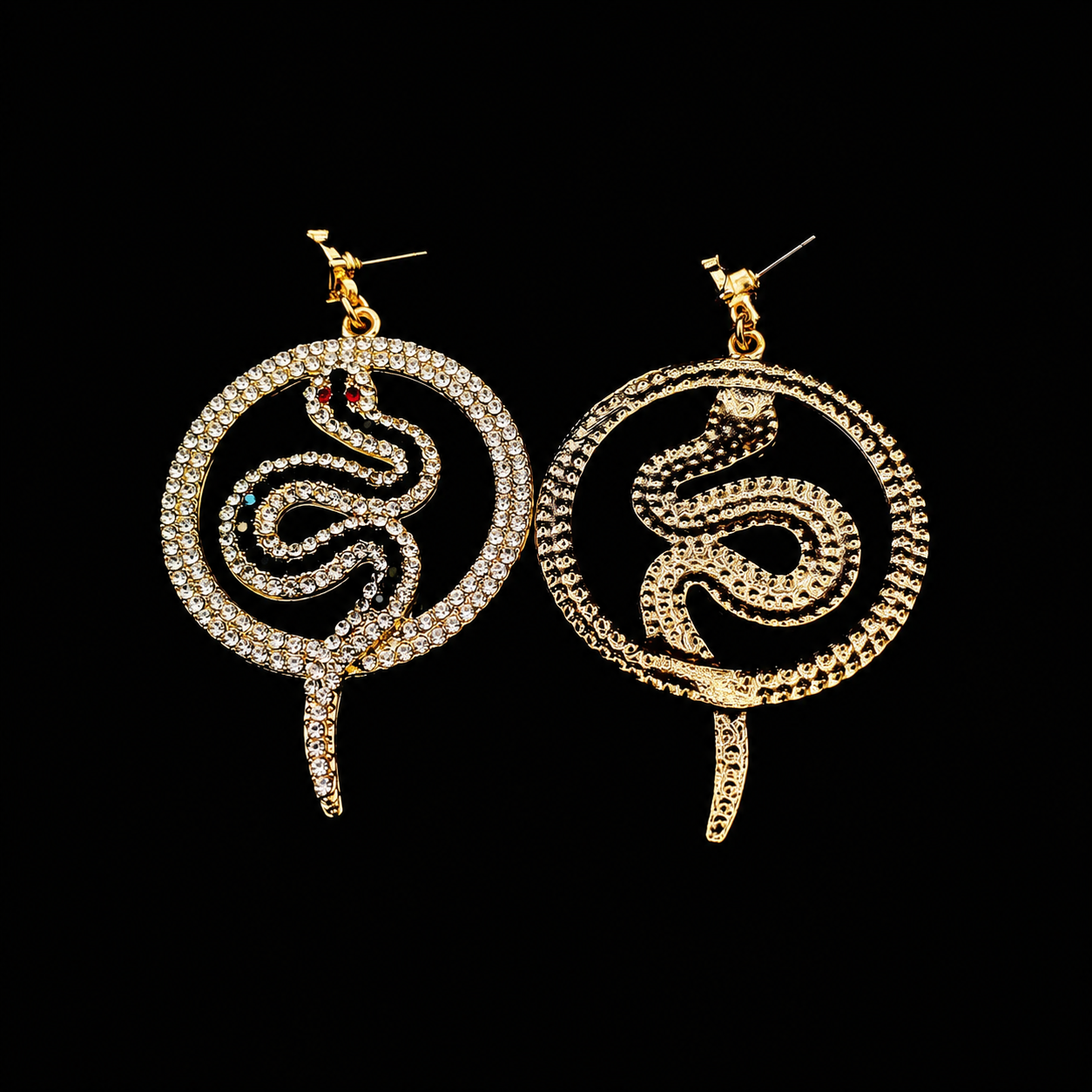 A pair of gold snake dangle earrings embellished with clear rhinestones, one earring featuring a solid gold snake and the other with a rhinestone-encrusted snake, set against a solid black background.
