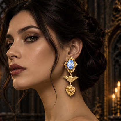 A woman in a black lace dress wears an ornate gold drop earring with a blue gemstone and heart-shaped pendant, posed in a dark, candle-lit gothic interior.