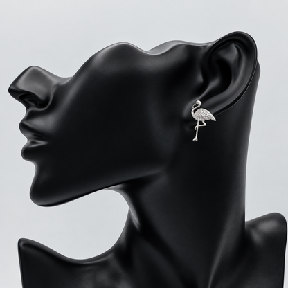 A silver-toned flamingo stud earring displayed on the ear of a matte black female mannequin head against a light gray background.