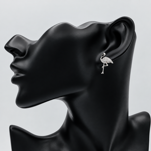 A silver-toned flamingo stud earring displayed on the ear of a matte black female mannequin head against a light gray background.