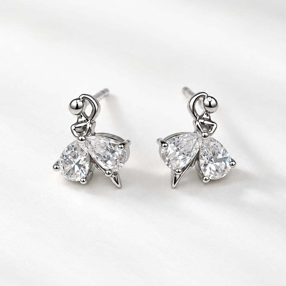 A pair of silver-toned butterfly stud earrings with clear teardrop-cut gemstones, displayed on a clean, light gray textured fabric background.