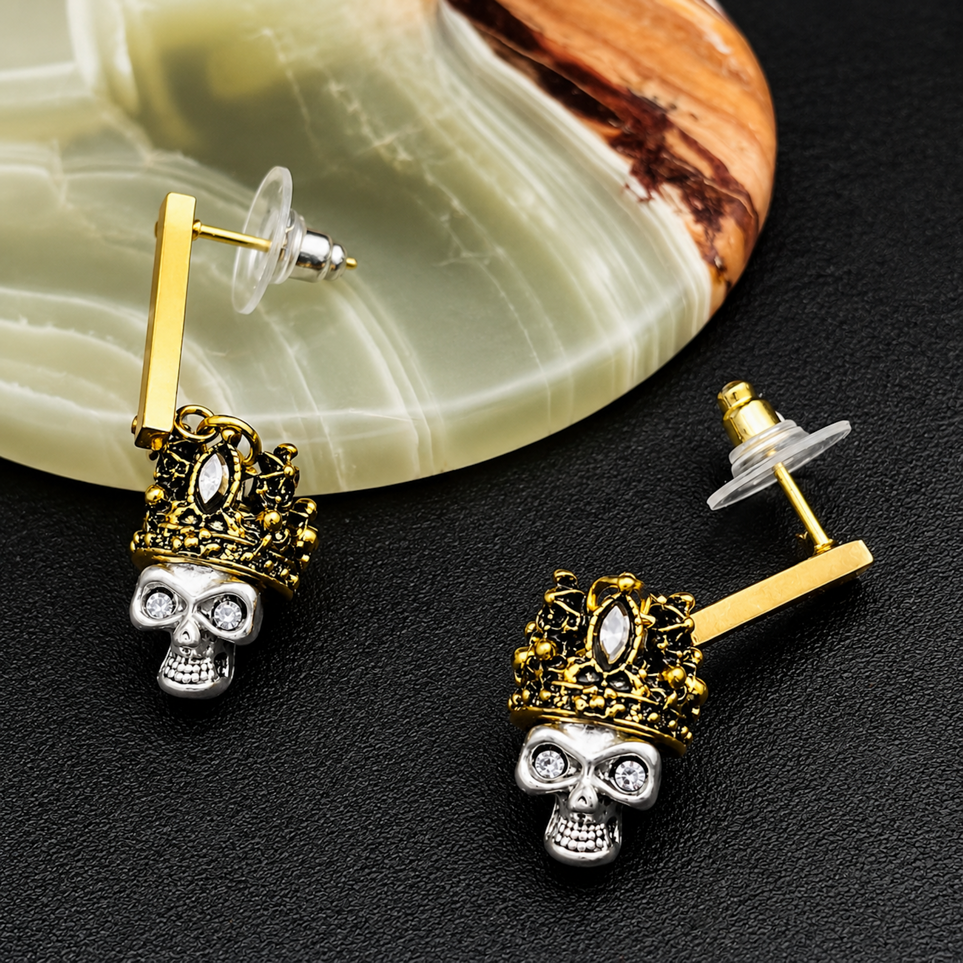 A pair of gold crown and silver skull stud earrings.