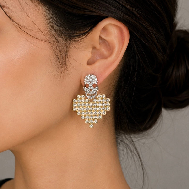 A close-up of a model's ear and neck wearing a dangling skull-shaped earring adorned with clear rhinestones and small red gemstone details.