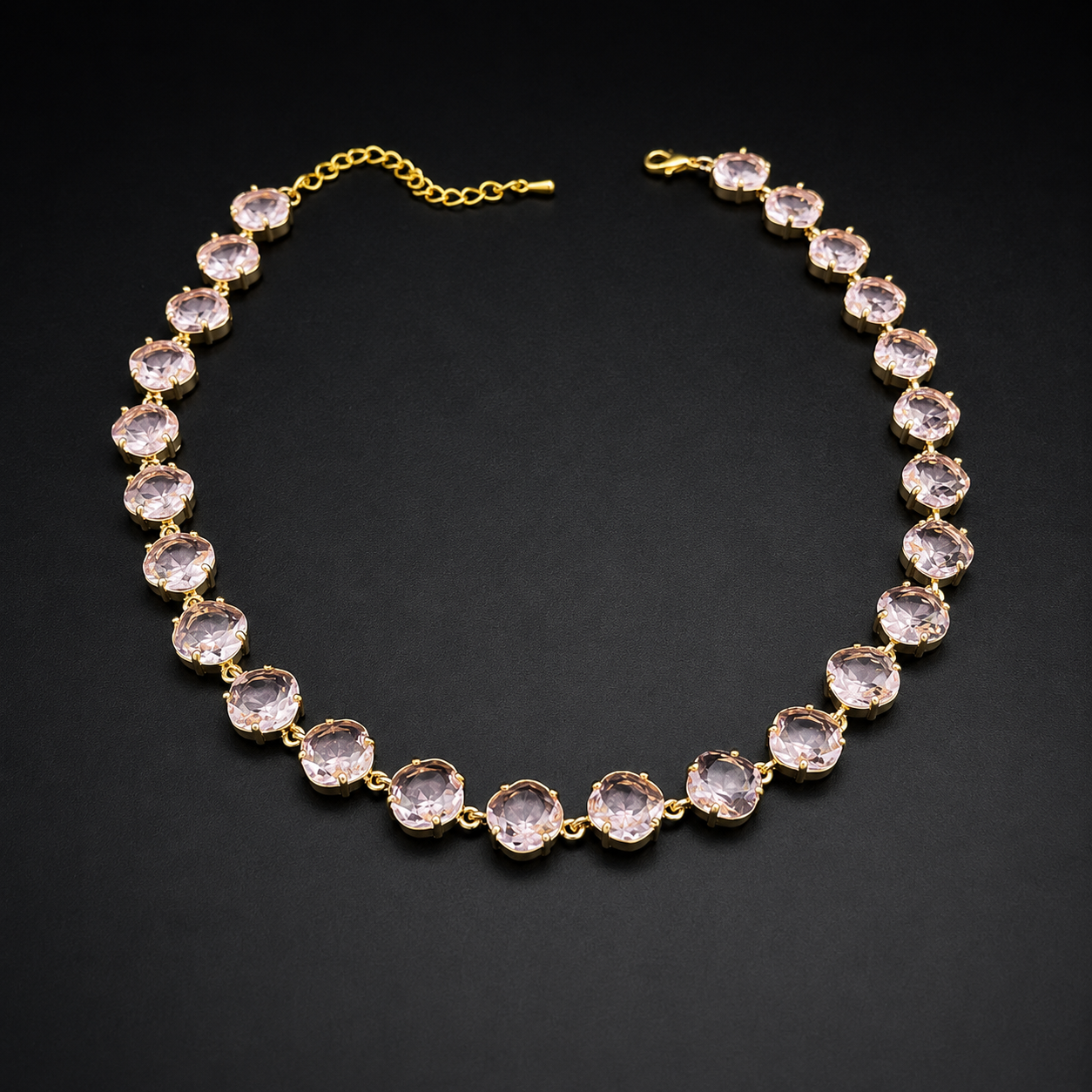 A gold-plated tennis necklace featuring round, faceted light pink gemstones, displayed on a dark textured background.